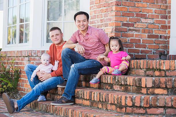 istock Two fathers with their young children sitting on steps 512825240