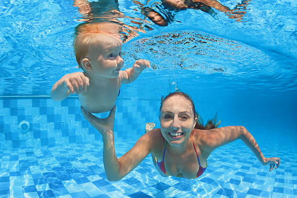istock Child swimming lesson - baby with moher dive underwater 512828274