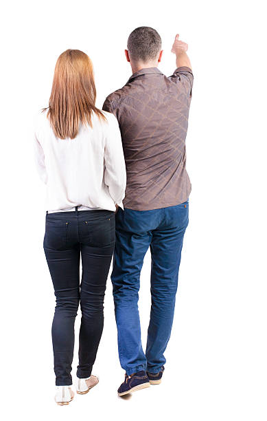 istock Back view of walking young couple (man and woman) pointing. 512835821