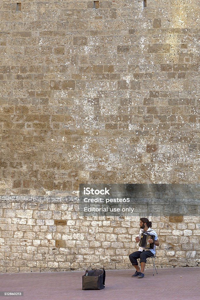 San Gimignano, Tuscany, street musician. Color image San Gimignano, Italy - August 4, 2014: San Gimignano, Tuscany, a street musician performing with an accordion in the historical center of the city. Photo taken in a public place. Accordion - Instrument Stock Photo