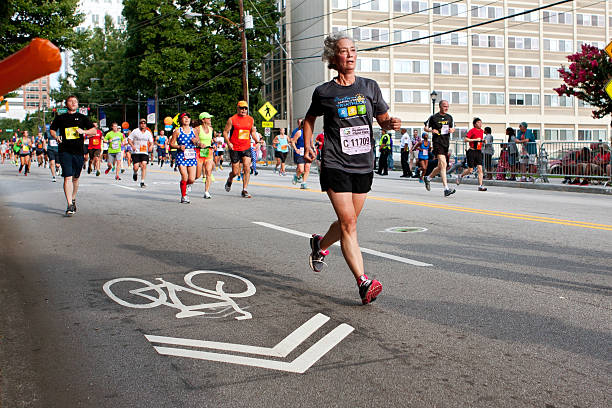 пожилая женщина работает в атланте peachtree road расы - atlanta pride стоковые фото и изображения