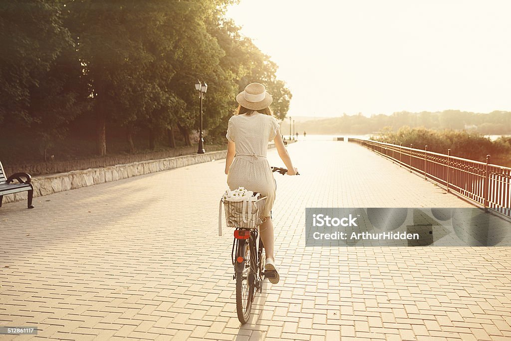 Girl riding a bicycle in park near the lake Girl riding a bicycle in park near the lake. Lightleak effect and instagram filter Adult Stock Photo