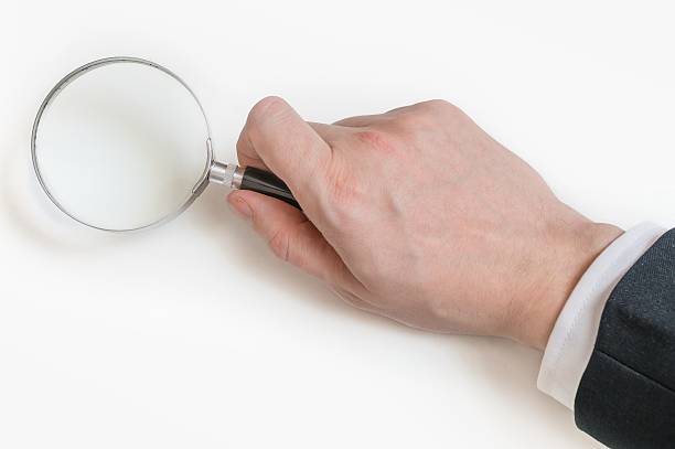 istock Man in suit holds magnifying glass. Isolated on white background 512883316