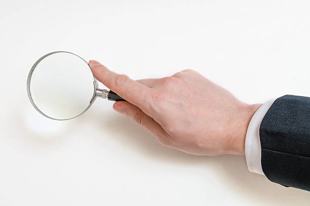 istock Man in suit holds magnifying glass. Isolated on white background 512883358