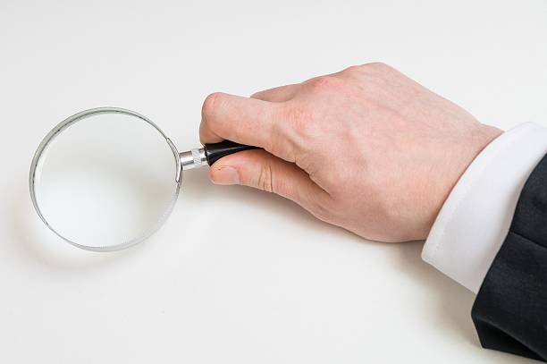 istock Man in suit holds magnifying glass. Isolated on white background 512883378