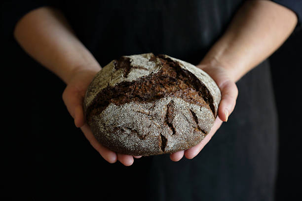 istock round whole dark bread in baker's hand 512883404