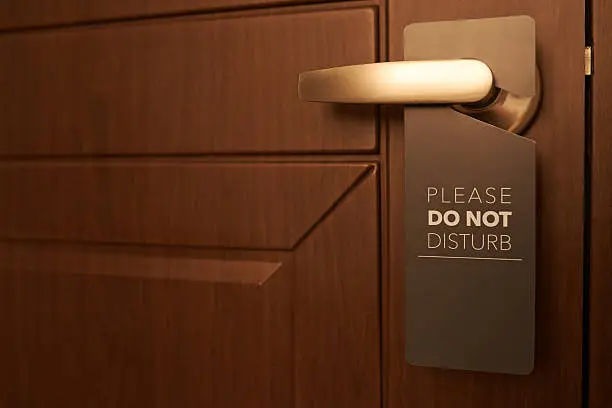 Closed door of hotel room with please do not disturb sign