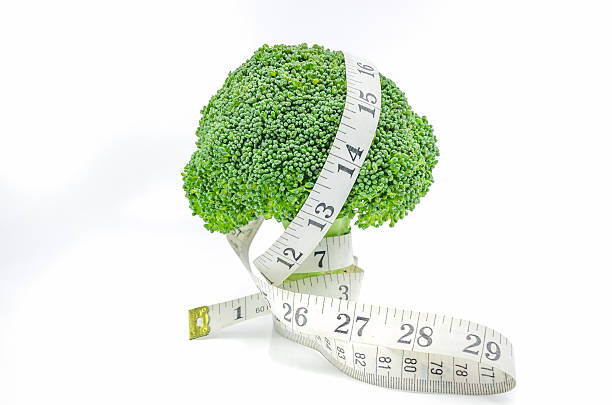 Measuring tape with broccoli. Live Healthy - Fresh raw broccoli with measuring tape on white background. perfect pear stock pictures, royalty-free photos & images