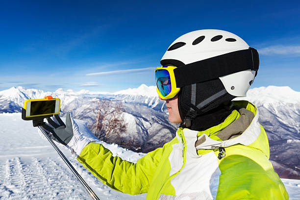 Portrait of woman skier in helmet and ski mask taking selfie