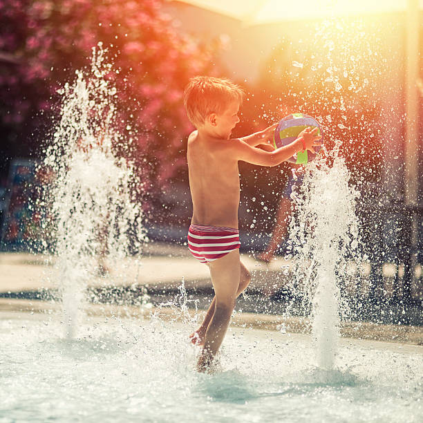 istock Little boy having fun in water park fountain pool 512886282