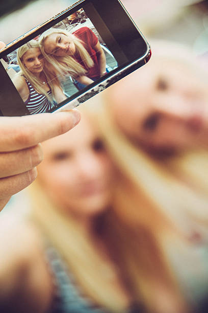 istock Two Beautiful Young Women Taking Self Portrait Outdoors, Selective Focus 512888046
