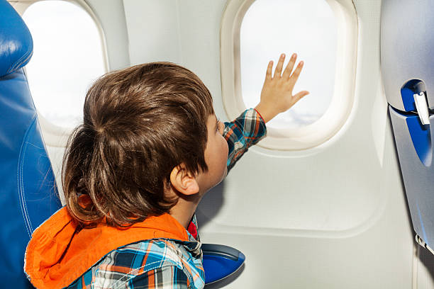 istock Little boy on airplane touch window with hand 512889070