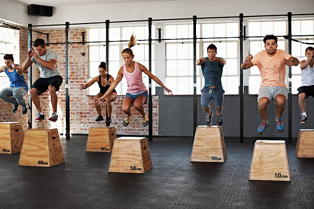 Getting the jump on good health Shot of a group of people jumping onto boxes in a gym class circuit training stock pictures, royalty-free photos & images