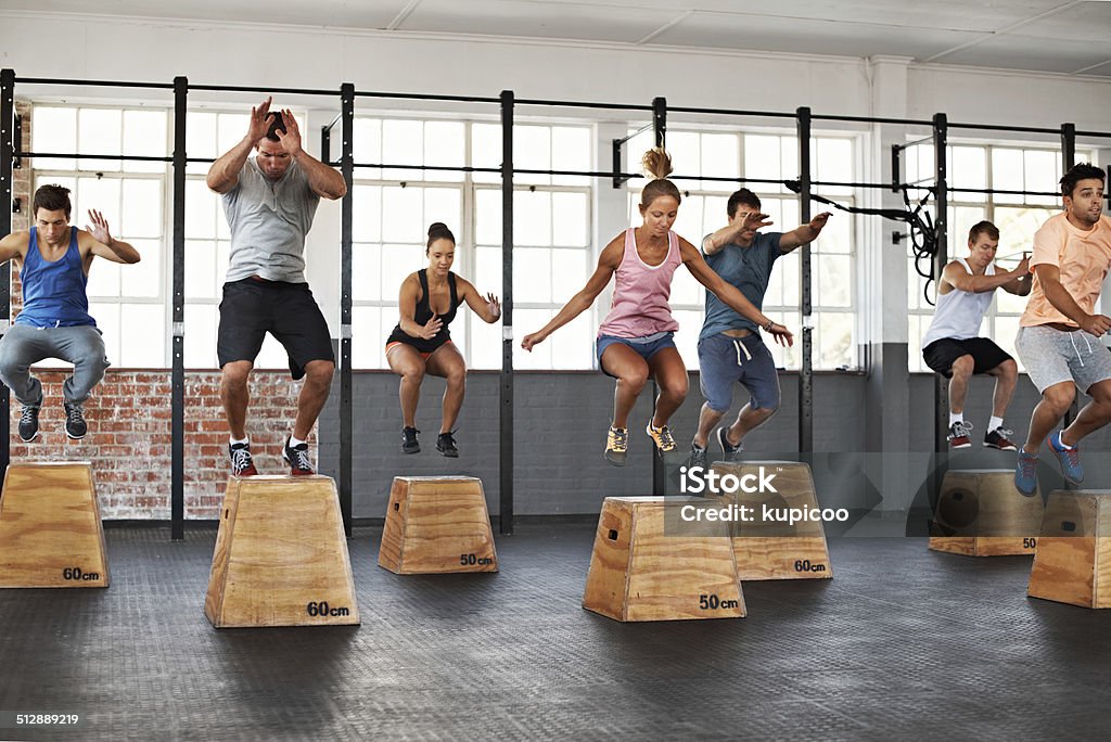 Getting the jump on fitness Shot of a group of people jumping onto boxes in a gym class Jumping Stock Photo