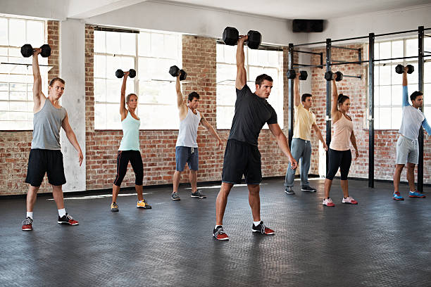 Building their strength together Shot of a group of people lifting dumbbells in a fitness class circuit training stock pictures, royalty-free photos & images
