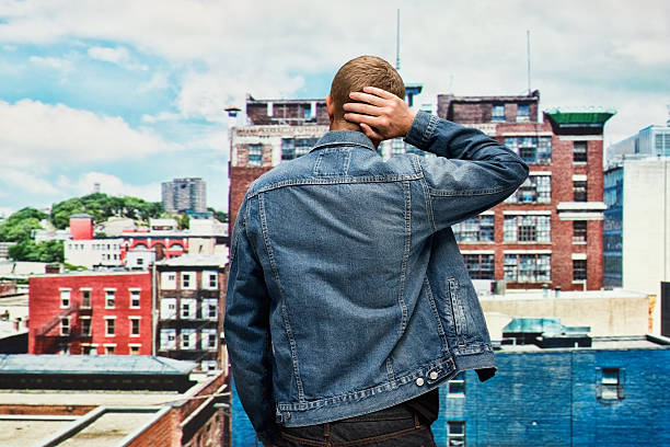 vista traseira do homem de pé e olhando longe - denim jacket - fotografias e filmes do acervo