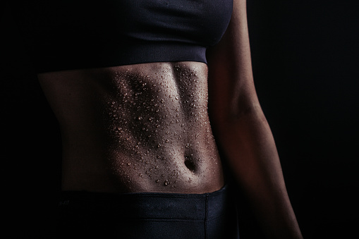 Photo of a young woman's abs covered up in sweat after intense workout