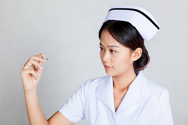istock Young Asian nurse look at  thermometer 512890001