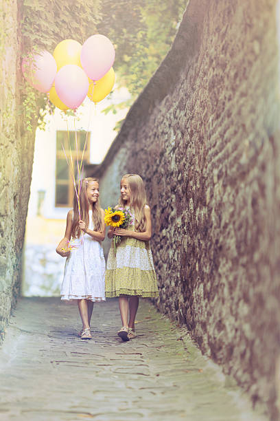 Cute girls and beautiful nature. Two little girls in floral dresses stand in the midst of nature. The white headband perfectly complements the delicate look of the younger sister.