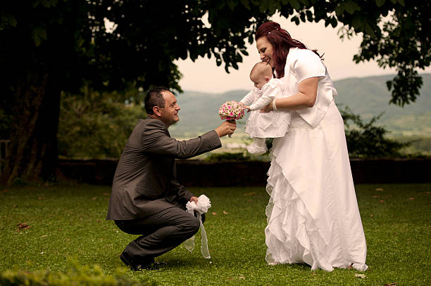 Wedding couple posing outdoor with their small daughter on their wedding day.