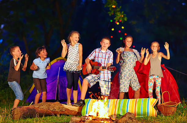 glückliche kinder tanzen rund um lagerfeuer - recreate stock-fotos und bilder