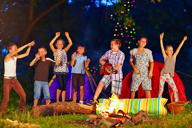 glückliche kinder tanzen rund um lagerfeuer - recreate stock-fotos und bilder