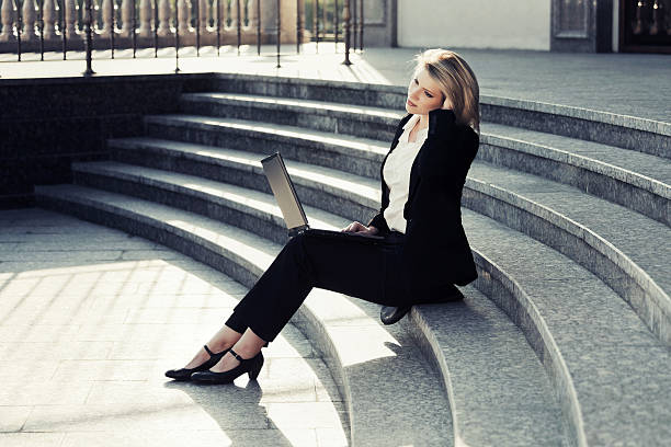 istock Young business woman using laptop on the steps 512895035