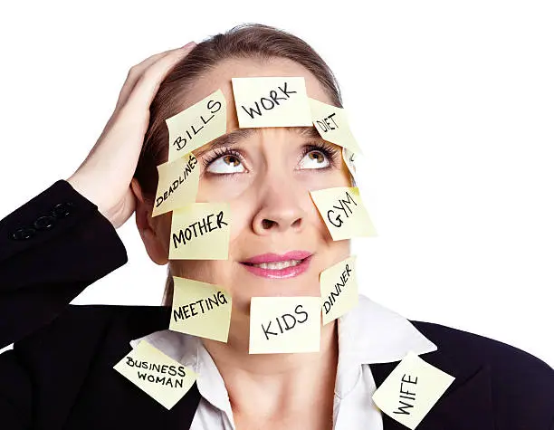 An overtired woman covered with adhesive-note reminders for all sorts of tasks looks stunned, rolling her eyes in exasperation. She simply cannot manage this much multitasking!