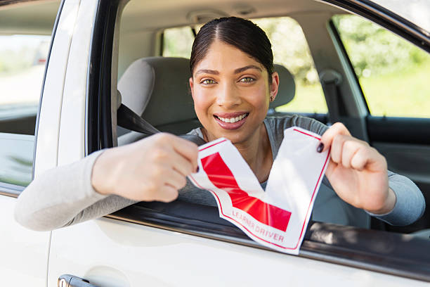 istock female driver tearing up her learner driver sign 512895942