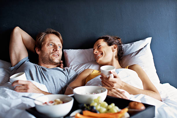 Making the most of their weekend time together Shot of a mature couple relaxing in bed with breakfast bed breakfast pictures stock pictures, royalty-free photos & images