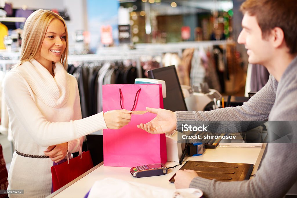 Payment Portrait of pretty woman giving credit card to shop assistant while paying for her purchase Adult Stock Photo