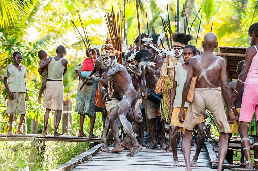 Jow Village, Asmat, New Guinea, Indonesia - June 28, 2012: The people of Asmat Village follow the ancestors embodied in spirit mask as they tour the village. The Doroe ceremony. 
