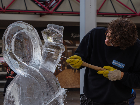 Almere, Netherlands - October 25, 2015: Ice sculptor in the townsquare of Almere. sculpts a figure. Once a year street artists gather to show of their skills to the public in the city.