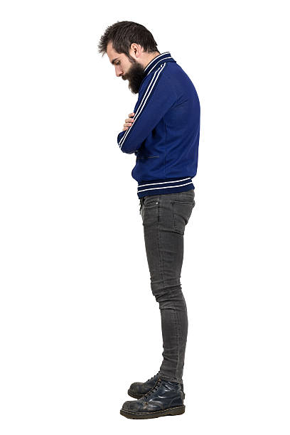 Profile view of bearded hipster in tracksuit jacket looking down