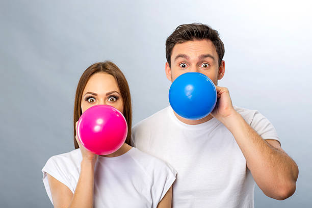istock Cheerful young couple blowing balloons 512908910