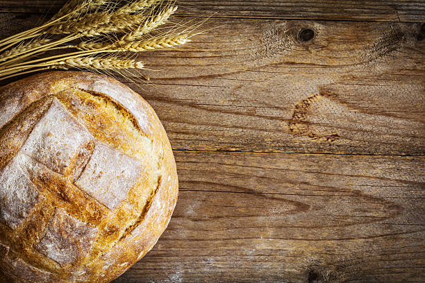istock Wooden background with rustic loaf of bread and wheat 512908918