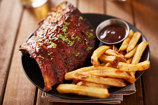 half rack barbecue rib platter with french fries on rustic wooden table