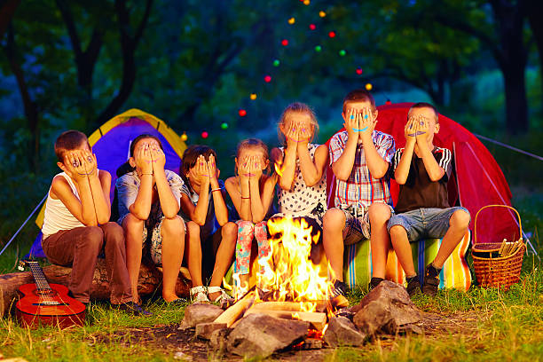 istock kids with painted faces on hands sitting around camp fire 512917669