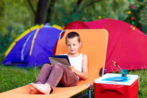 garoto no acampamento de verão, relaxante com tablet - recreate - fotografias e filmes do acervo