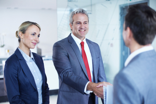 Shot of two businesspeople shaking hands while having a standing in an office