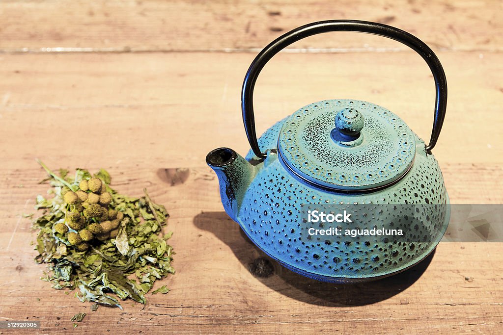 Blue teapot and chamomile plant Blue ceramics teapot, chamomile and tea leaves. Aromatherapy Stock Photo