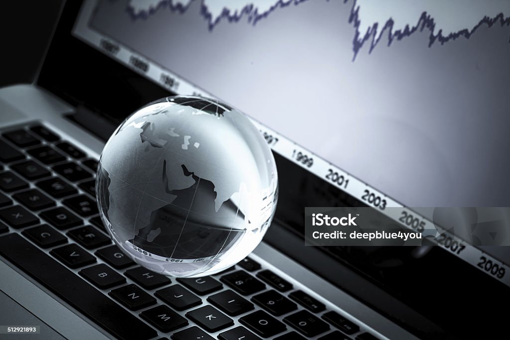 Globe on laptop keyboard with chart in the background Globe on laptop with chart in the background Chart Stock Photo