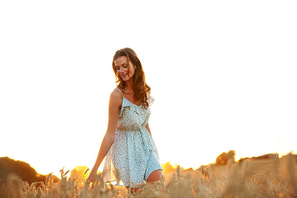 A young woman touching crops as she walks through a field