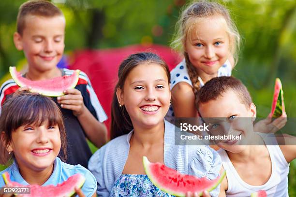 Happy Friends Eating Watermelon Outdoors Stock Photo - Download Image Now - Summer Camp, Teenager, Camping