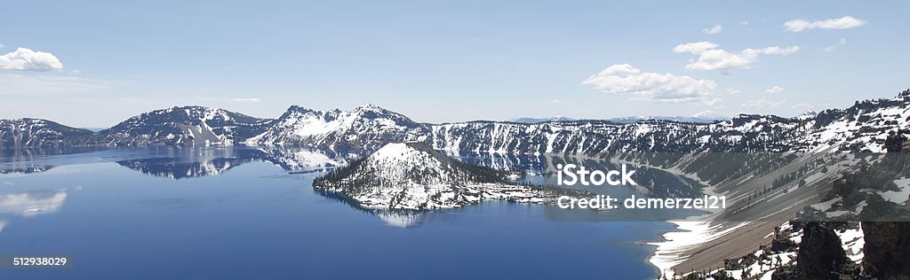 Crater Lake National Park, Oregon Clear blue water of Crater Lake National Park in Oregon during early spring with some snow left from winter. Wizard Island in the distance. At The Edge Of Stock Photo