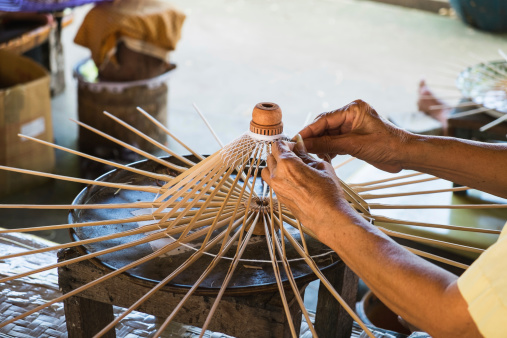 Woman hands weaving threads at a loom.