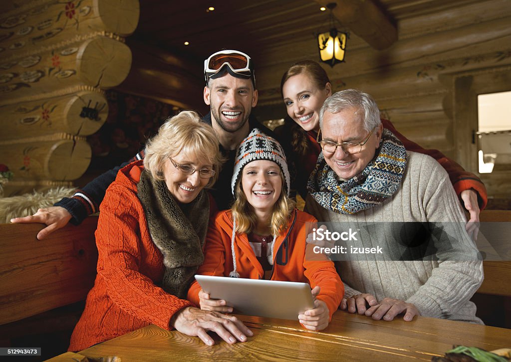 Family using digital tablet Multi-generation family sitting in a mountain restaurant after skiing and using a digital tablet together. Winter Stock Photo