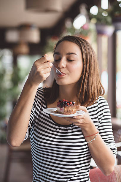 Young woman eating strawberry cheesecake stock photo