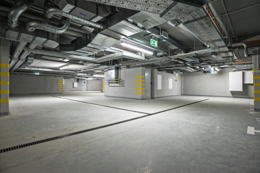 Empty, new, underground parking garage interior. At the ceiling is located electrical system and air condition.