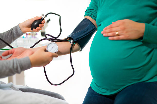 pregnant woman at doctor's office having pressure measured - huisarts druk stockfoto's en -beelden